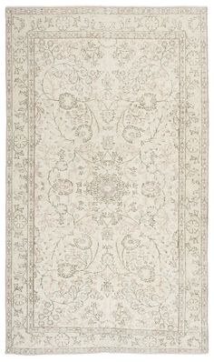 a white rug with an intricate design on the center and sides, in various colors