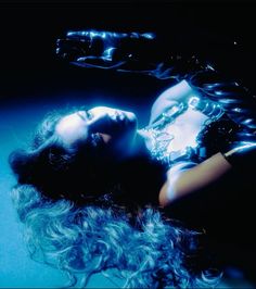 a woman laying on the ground with her hair blowing in the wind and wearing chains around her neck