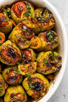 a white bowl filled with stuffed peppers and garnished with parsley on top