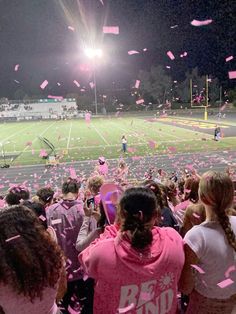 a group of people standing on top of a field covered in pink confetti