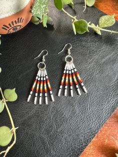 Southwest Sunset Fringe Dangle Earrings Design: These earrings are very lightweight, colorful and playful in a southwest inspired style.  Featuring 5 hand beaded head pins dangling from a silver finish ring and fishhook earring backing. Length: Approx. 2.5" drop length Colors: These beaded earrings feature a sunset like fade of glossy white, black, red, orange, yellow shimmer, white, and silver high quality glass beads hand strung onto silver finish nickel free metal components. **Notice: All earrings are FINAL SALE due to health standards. ** Photo disclaimer: All bead design will remain as pictured; color richness could vary.  Colors may vary depending on screen resolutions and devices viewing this listing.  All item photos and videos are taken on iPhone in a natural light setting to sta Sunset Minimalist, Southwest Sunset, Earrings Western, Minimalist Bar, Beaded Earrings Native, Bead Dangle Earrings, Earrings Design, Fish Hook Earrings, Beaded Hoop Earrings