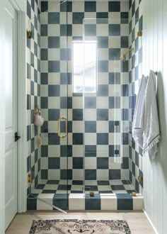 a bathroom with black and white tiles on the shower wall, rugs and towels