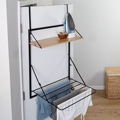 an ironing board and clothes hanging on a rack in the corner of a room