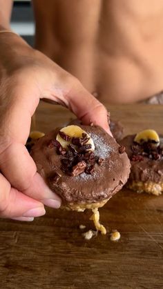 a person is picking up some kind of chocolate cookie with nuts on the top and bottom