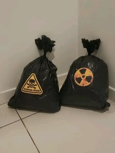 two black bags with warning signs on them sitting next to each other in a corner