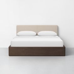 a bed with two pillows on top of it in a white room next to a wall