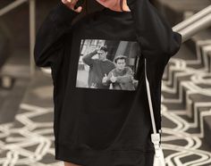 a woman talking on her cell phone while wearing a black sweatshirt with an image of two men