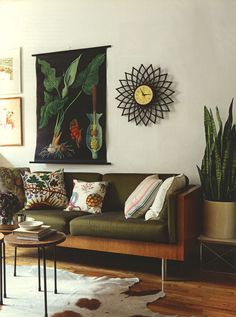 a living room filled with lots of furniture next to a wall mounted clock and plants