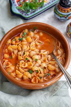 a bowl filled with pasta and garnished with parsley on the table next to other dishes