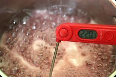 a digital thermometer in a pot full of boiling hot liquid with water on it