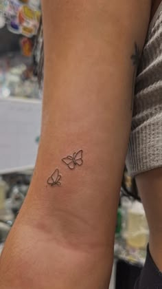 a woman's arm with two butterflies tattoo on the left side of her arm