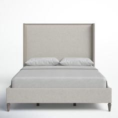 an upholstered bed with two pillows on it