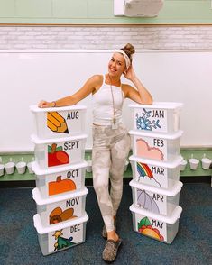 a woman standing next to stacks of plastic containers with pictures on the sides and words painted on them