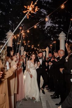 a bride and groom walk down the aisle with sparklers