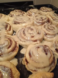 cinnamon rolls with icing sitting on top of a pan