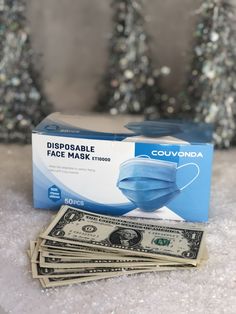 a pack of disposable face masks sitting on top of $ 50 bills