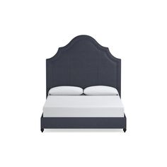 an upholstered bed with white sheets and pillows on the headboard is shown