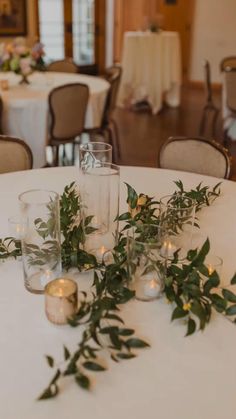 the table is set up with candles and greenery for an elegant dinnereonary