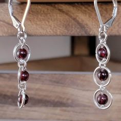 These earrings are a gorgeous deep red genuine Garnet, January's birthstone. These will become a favorite accessory or a treasured gift. The earrings are 2 inches from top to bottom. They are 3/8inch wide.  Lever back closures are made of Sterling Silver. Hoops themselves nickel free alloy. These earrings are beautiful and really shine in the daylight with the warm sun. The light bounces off, showing more depth of color throughout the stones. These delicate earrings are the perfect accompaniment Garnet Drop Earrings With Ear Wire, Burgundy Dangle Earrings, Garnet Dangle Earrings For Pierced Ears, Handmade Garnet Drop Earrings, Nickel-free Garnet Drop Earrings, Red Garnet Wire Wrapped Earrings, Garnet Drop Earrings With Matching Set, Handmade Burgundy Dangle Earrings, Handmade Burgundy Drop Earrings