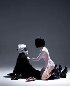 a man kneeling down next to a woman with a helmet on her head and legs