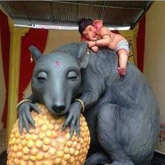 a statue of a man riding on the back of a giant gray rat next to a baby