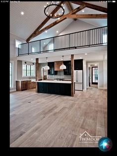 an open concept kitchen and living room with wood flooring, white walls and beams