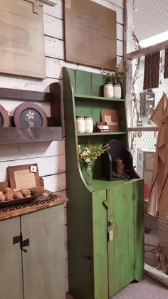 an old green cabinet in the corner of a room with other items on shelves and cupboards