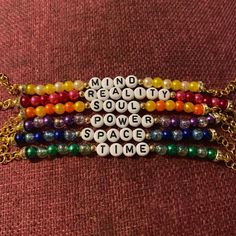 four bracelets with words written on them and beads attached to each other, all in different colors