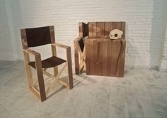 two wooden chairs sitting next to each other in front of a white brick wall with a skull on it