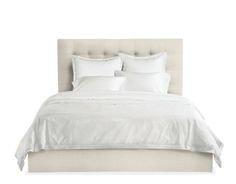 a bed with white linens and pillows on it's headboard, against a white background