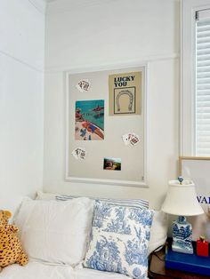 a white couch with blue and white pillows on top of it next to a window