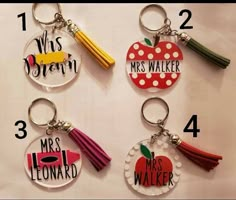 four keychains with different designs on them, one has an apple and the other has