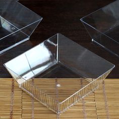 three clear boxes sitting on top of a bamboo mat