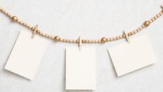 three blank tags hanging on a string with wooden bead necklaces and beads around them