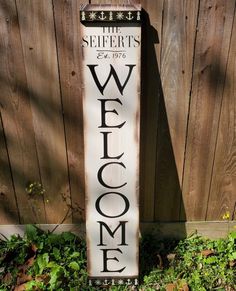 a welcome sign sitting in front of a wooden fence