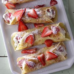 strawberry crepes with powdered sugar and fresh strawberries on top are ready to be eaten