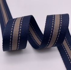 a close up of a blue and beige ribbon on a white background with stitching