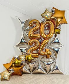 the number 20 is surrounded by balloons and star shaped stars in gold, silver and copper