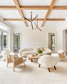 a living room with white furniture and wood beams