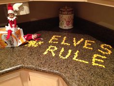 the elf is laying on the kitchen counter next to the rules written on the floor