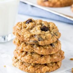 a stack of oatmeal raisin cookies next to a glass of milk