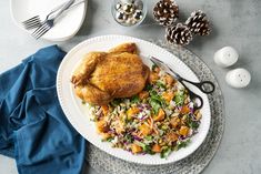 a white plate topped with chicken next to a salad and pineconi on top of a table