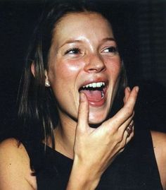 a woman is making a silly face while holding her hand up to her mouth