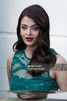 a woman with long dark hair wearing a green dress and holding a silver platter