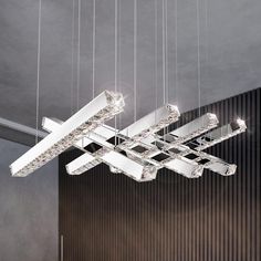 a modern chandelier hanging from the ceiling in a room with dark walls and flooring