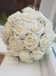 a bouquet of white roses and pearls sits on a window sill