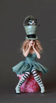 a doll is sitting on top of a ball with her hands to her face, wearing a green dress and striped tights