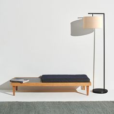 a bed sitting next to a lamp on top of a wooden table in front of a white wall