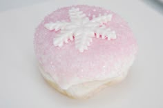 a pink and white frosted cookie with snowflakes on it's top