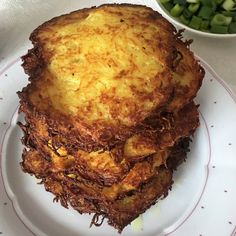 a stack of fried food sitting on top of a white plate next to a bowl of green beans